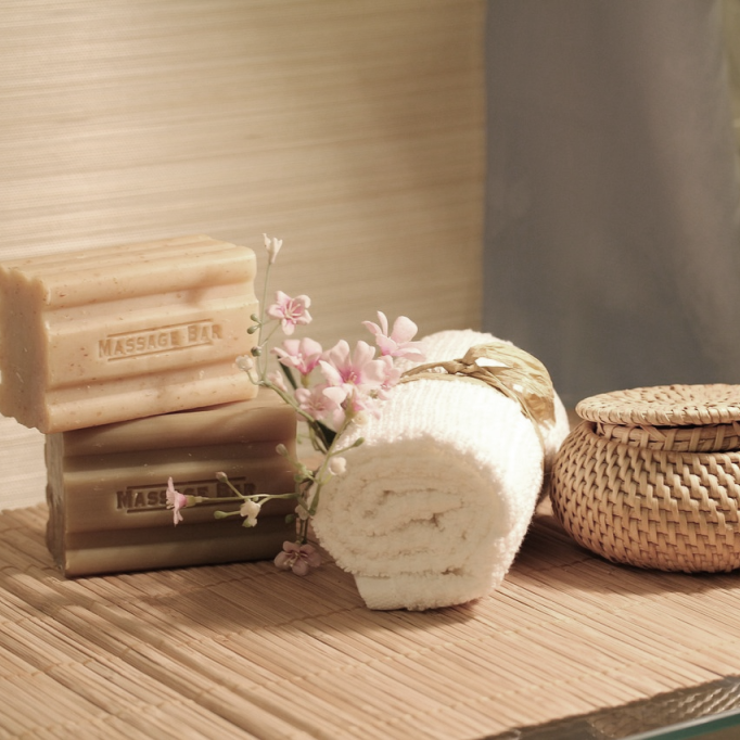 Spa essentials with natural massage soap, rolled towel, and flowers for wellness and relaxation therapy